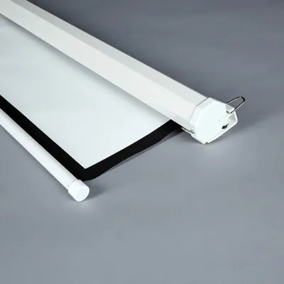 A close-up view of a white projector screen that is partially rolled up, showing the black border and the roller mechanism.