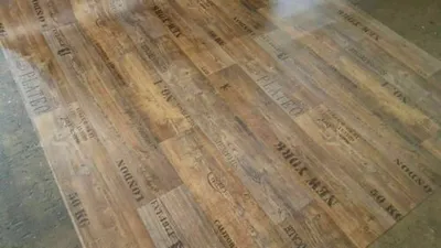 A roll of vinyl flooring with a wood plank design and printed text.