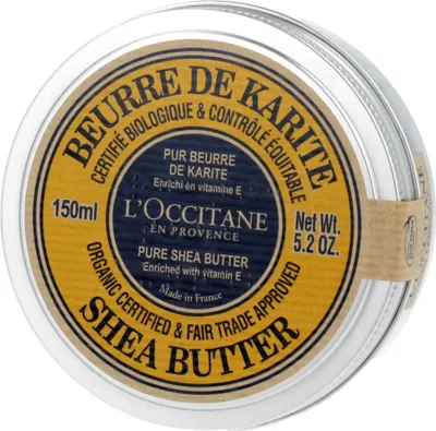 A close-up, top-down view of a round metal tin of L'Occitane Shea Butter.