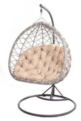 A hanging egg chair with a beige cushion, shown in a studio setting against a white background.