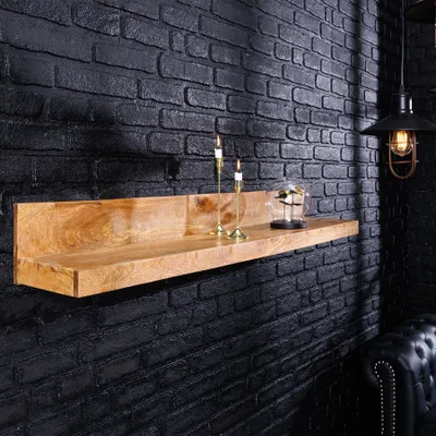 A wooden shelf mounted on a black brick wall, decorated with two candles and a glass display.