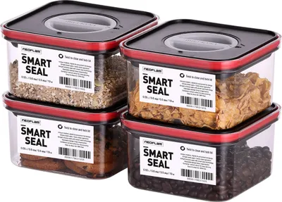 Four square food storage containers stacked in two columns, each with a black lid and red trim. Labels on the front of each container indicate the brand and product name.