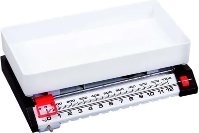 A close-up studio shot of a mechanical kitchen scale with a white tray and a black base.