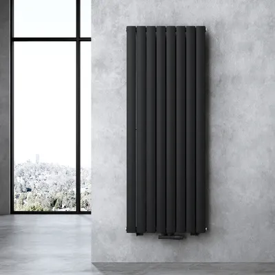 A modern bathroom radiator is mounted on a concrete wall next to a large window overlooking a snowy landscape.