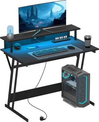 A gaming desk setup with a monitor, keyboard, mouse, and computer tower, illuminated by blue LED lights.