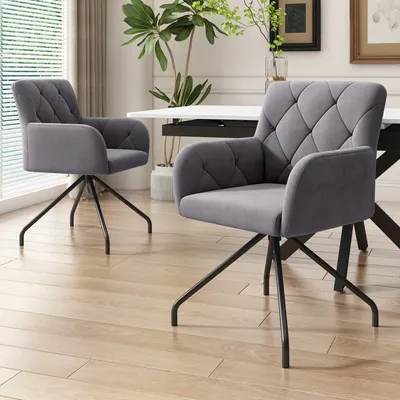Two gray upholstered dining chairs with black metal legs are placed on a light wood floor in a dining room setting.