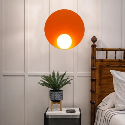 A bedroom scene with a pendant light, a nightstand with a plant, and a bed.