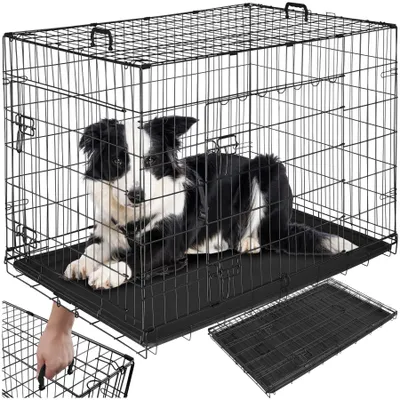 A black wire dog crate with a black and white border collie dog inside. A hand is shown reaching into the crate from the bottom left.