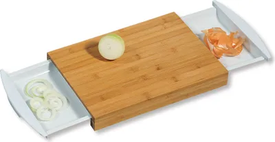 A bamboo cutting board with two white pull-out drawers, one containing sliced onions and the other onion peels.