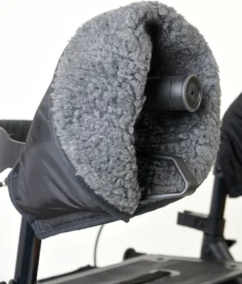 A close-up shot of a gray, fuzzy handwarmer attached to the handle of a walker.