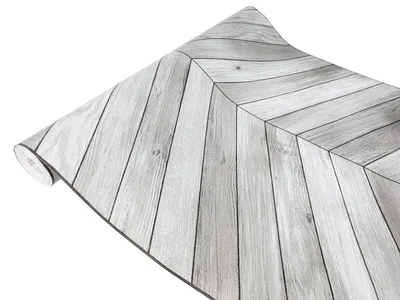 A roll of self-adhesive wallpaper with a wood plank pattern, laid out diagonally.