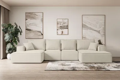 A modern living room with a large modular beige sofa, abstract art on the wall, and a potted plant.