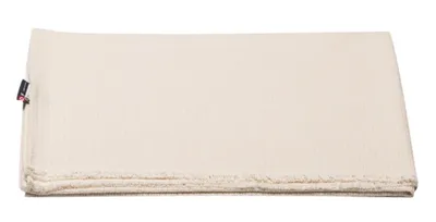 A folded cream-colored blanket with a small black tag on the left side.