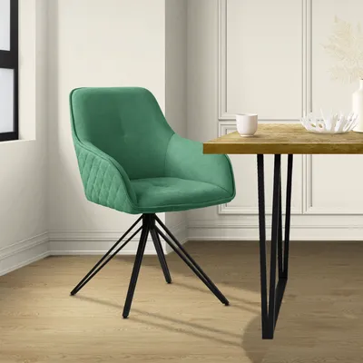 A green swivel chair with a quilted seat and back is placed next to a wooden table with black legs. The scene is set in a dining room with light-colored walls and wooden flooring.