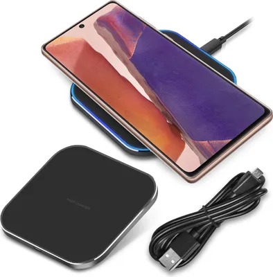 A smartphone is wirelessly charging on a charging pad, with a charging cable nearby.