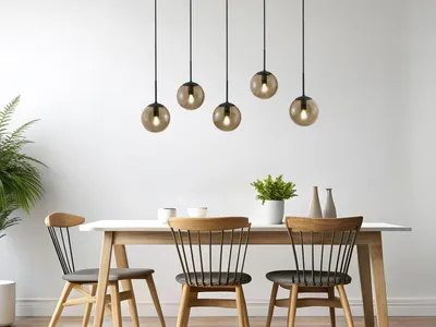 A dining room with a table and chairs, illuminated by a multi-pendant light fixture.