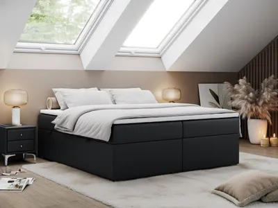 A bedroom with a bed, nightstand, and lamps under skylights.