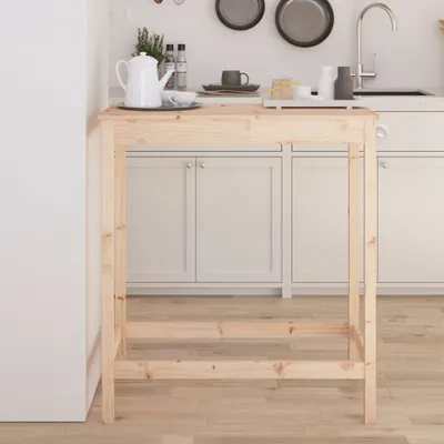 A wooden bar table in a kitchen setting, with cabinets and a sink visible in the background.