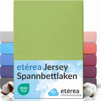 A product image showcasing a green jersey fitted sheet with multiple other colored fitted sheets stacked behind it, along with cotton bolls in the foreground.