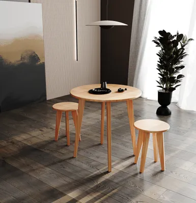 A round wooden dining table with two stools set on a dark wooden floor, in a modern room with a tall plant and abstract art on the wall.