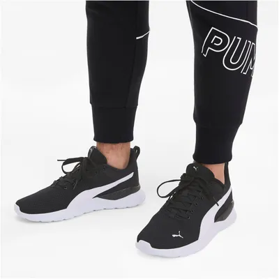 A person wearing Puma sneakers and black pants.
