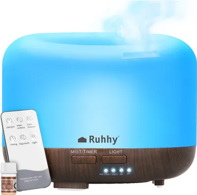 A blue and wood-grain essential oil diffuser with a remote control and a small bottle of oil.