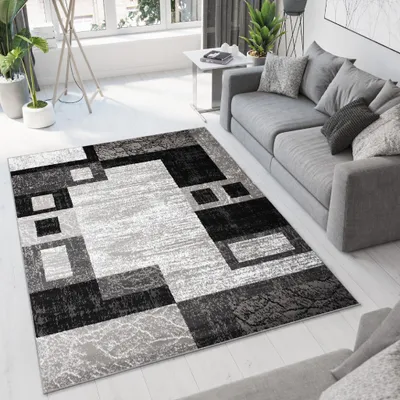 A modern living room with a gray sofa and a geometric patterned rug.