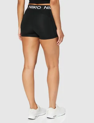 A woman wearing black Nike shorts and white sneakers, shown from the back.