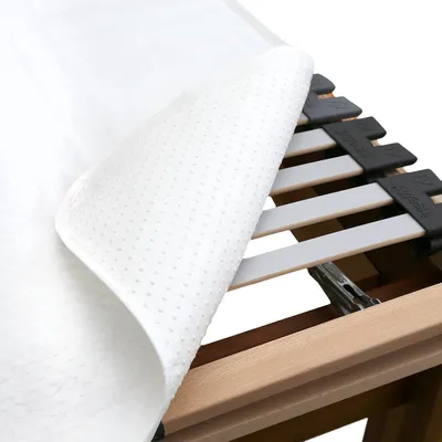 A close-up view of a mattress protector laid over a slatted bed base.
