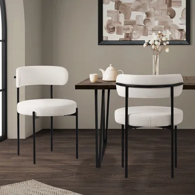 Two white dining chairs with black metal legs are placed around a wooden dining table, with a teapot and cup on the table.