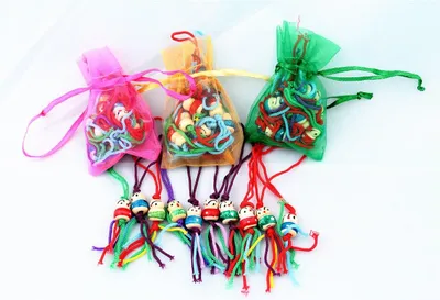 Three small organza bags filled with small wooden owl charms and colorful strings, with the charms hanging out of the bags.