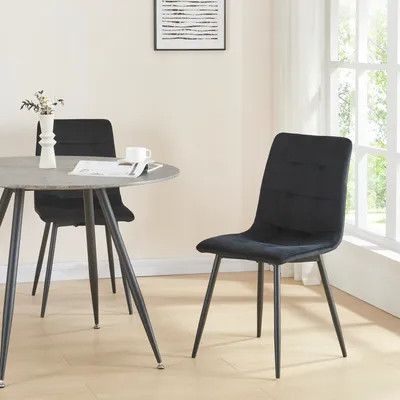 A dining set with two black chairs and a round table in a room with a window.