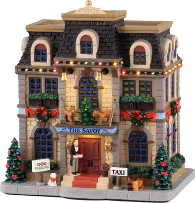 A miniature Christmas village building, "The Savoy", decorated with lights and festive wreaths.