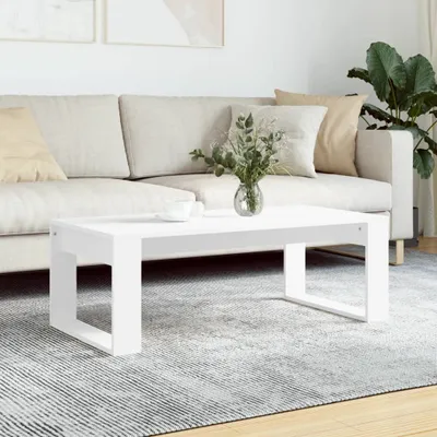 A white coffee table is placed on a rug in front of a sofa.