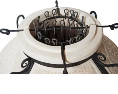 Close-up of the top opening of a tandoor oven with skewers inserted.