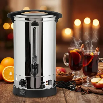 A stainless steel hot beverage dispenser is shown on a wooden table, with two glasses of mulled wine, oranges, apples, cinnamon sticks, and star anise in the background.