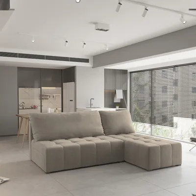 A modern living room with a sectional sofa, kitchen cabinets, and a window with blinds.