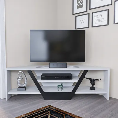 A TV stand in a corner of a room, with a TV on top and decorative items on the shelves.