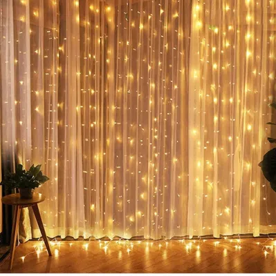 A curtain of warm white fairy lights hanging behind sheer curtains.