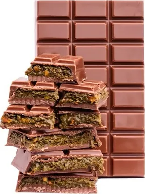 A stack of broken chocolate pieces with a filling, in front of a full chocolate bar.