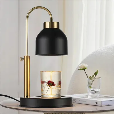 A candle warmer lamp is placed on a table next to a small vase with a flower.