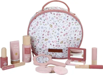 A wooden toy makeup set arranged in front of a floral patterned cosmetic bag.