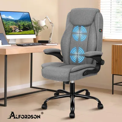 A gray office chair is placed next to a wooden desk with a computer and a lamp.