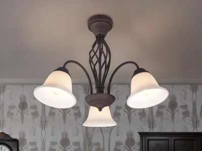 A ceiling light fixture with three lampshades is shown against a wall with patterned wallpaper.