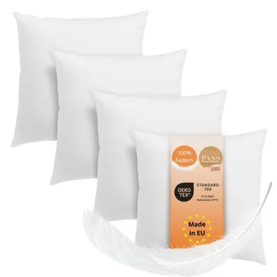 Four white pillows are arranged in a staggered formation, with a feather and a product information tag visible.