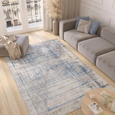A modern living room with a sofa, rug, ottoman, and coffee table.