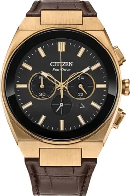 A close-up, front-facing studio shot of a gold Citizen Eco-Drive watch with a black dial and a brown leather strap.