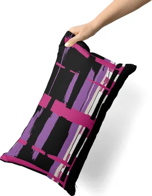 A hand holding a pillow with a colorful abstract pattern.