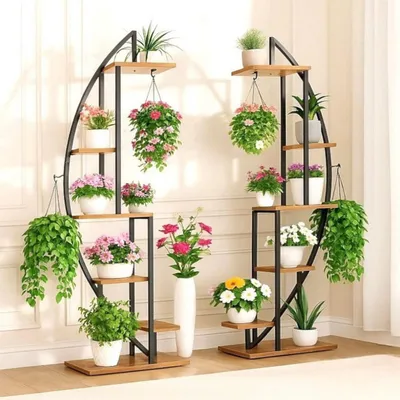 Two modern, multi-tiered plant stands filled with various potted plants and hanging plants, displayed indoors against a lightly textured wall.