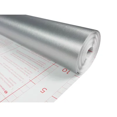A roll of silver brushed metallic self-adhesive foil is partially unrolled, showing grid lines and text on the backing paper.